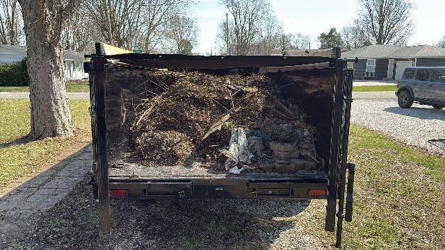A truck bed filled with brown yard debris, parked on a driveway.