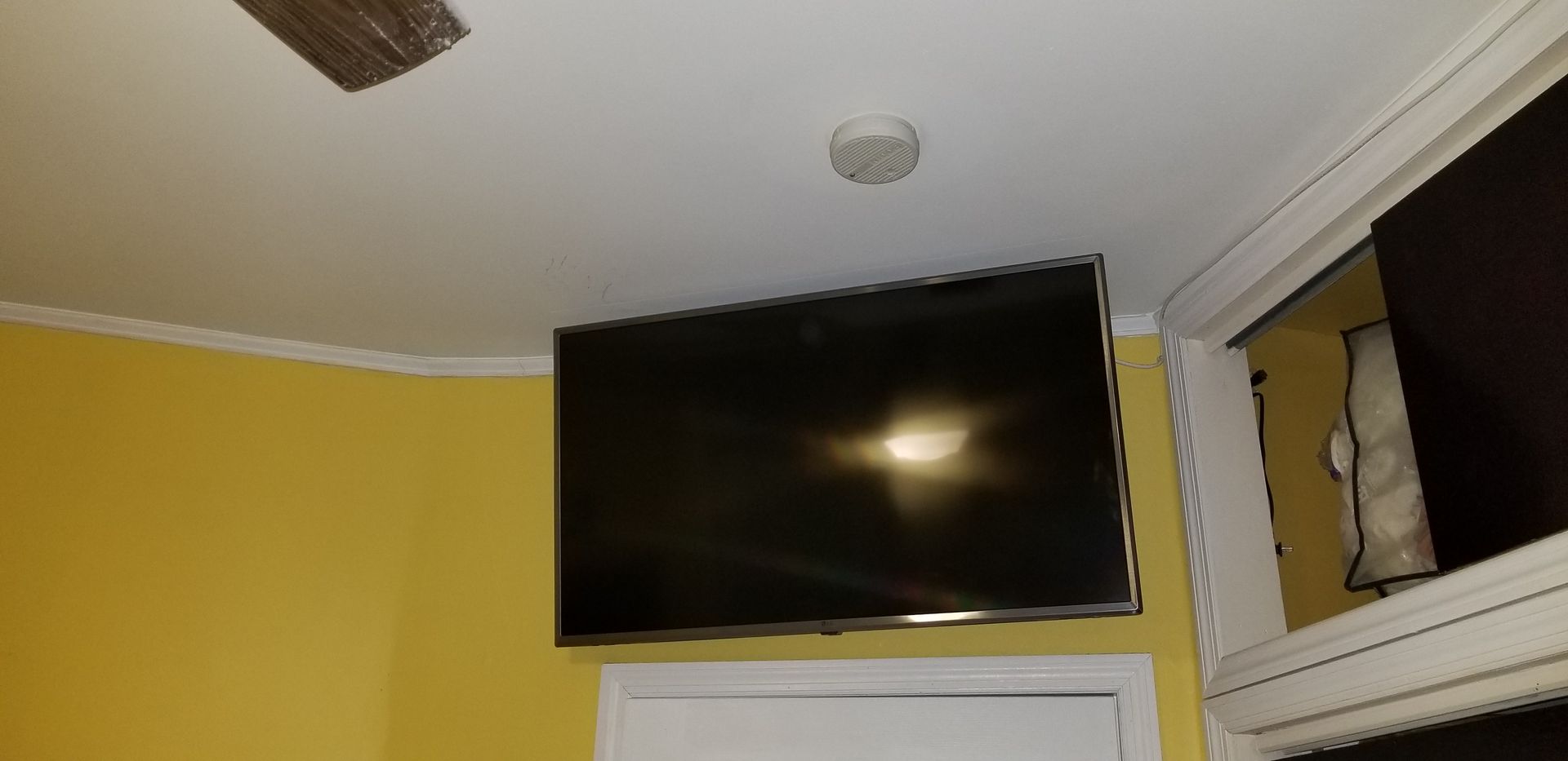 A flat screen tv is hanging from the ceiling in a room.