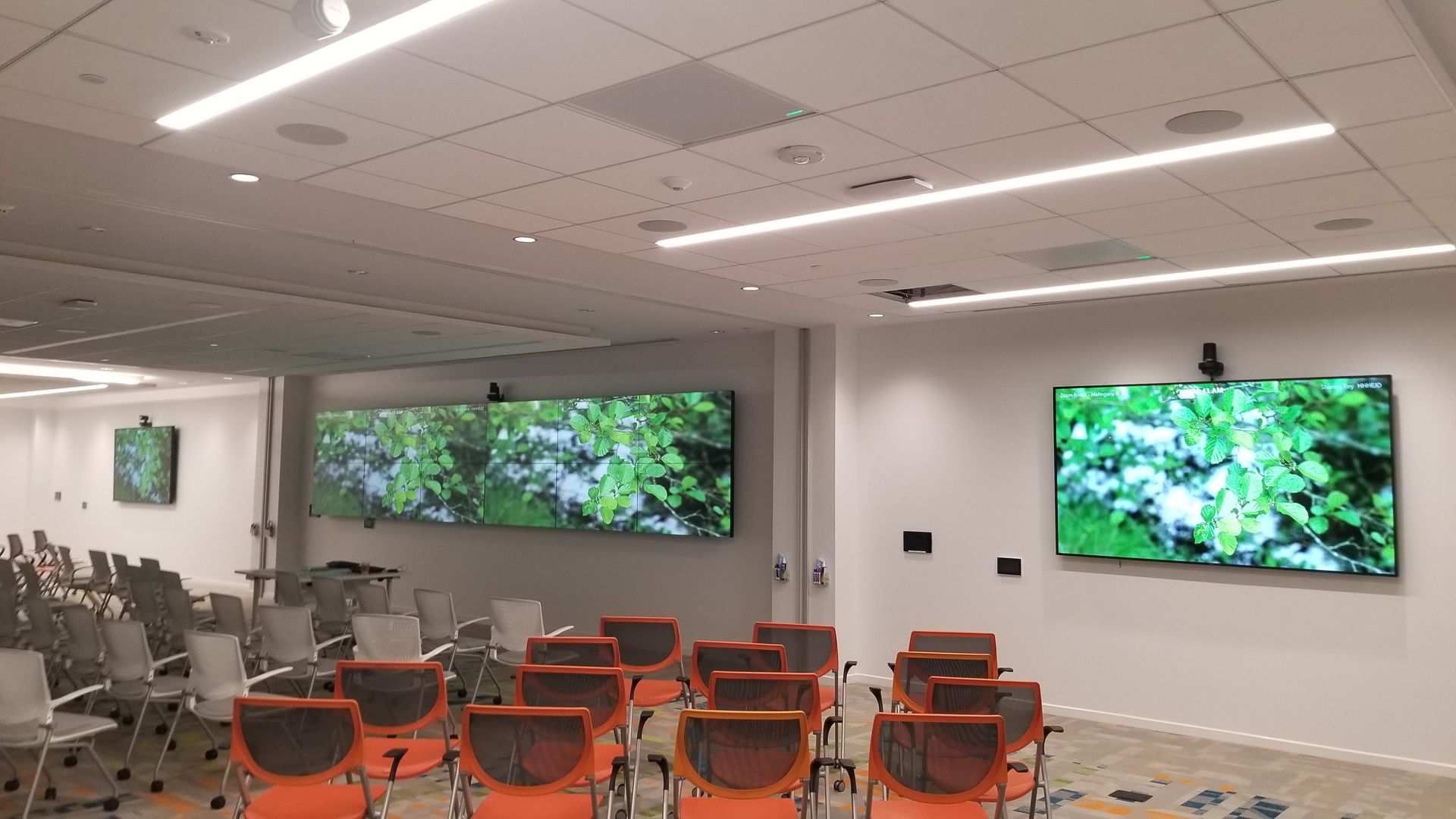 A conference room with rows of chairs and a large screen on the wall.