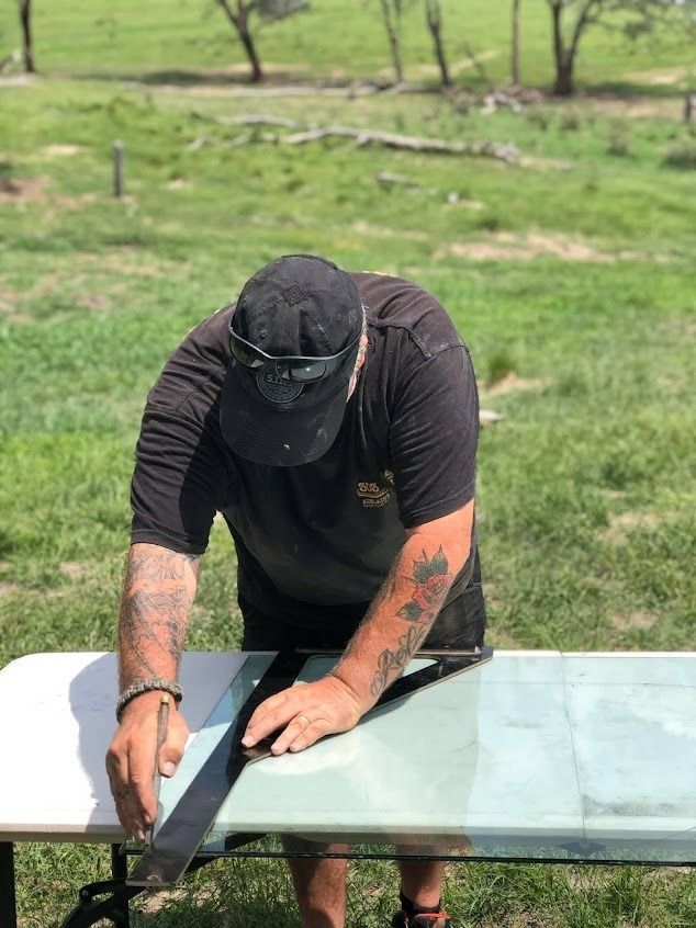Man in Black Shirt, Hat, Tattoos, Using a Square to Measure a Dark Strip — Road Runner Windscreens in South Grafton, NSW