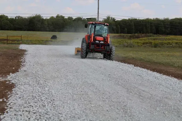 A red tractor working on a freshly laid gravel driveway in rural Texas.