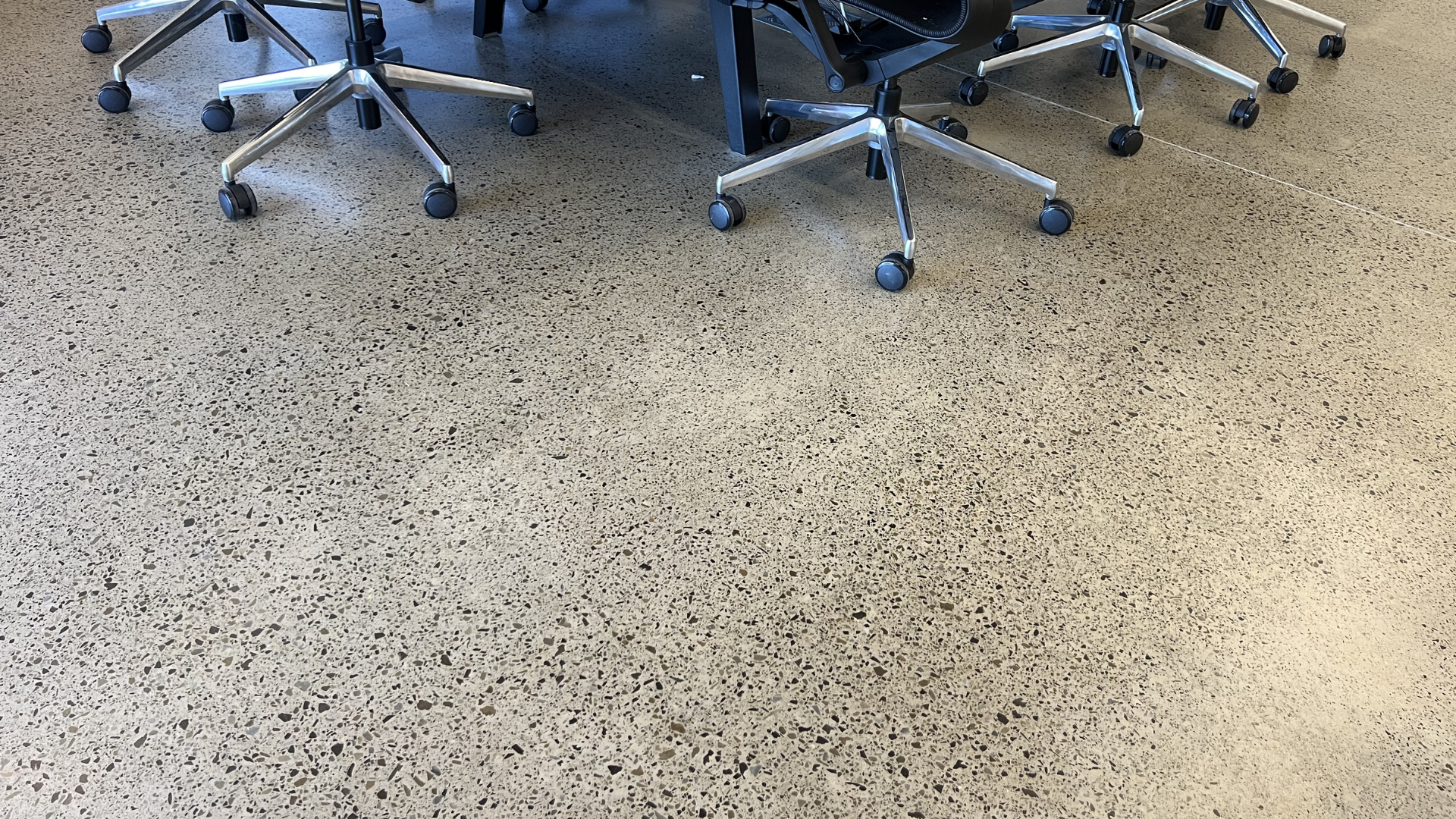 Office chair wheels on a speckled floor indoors