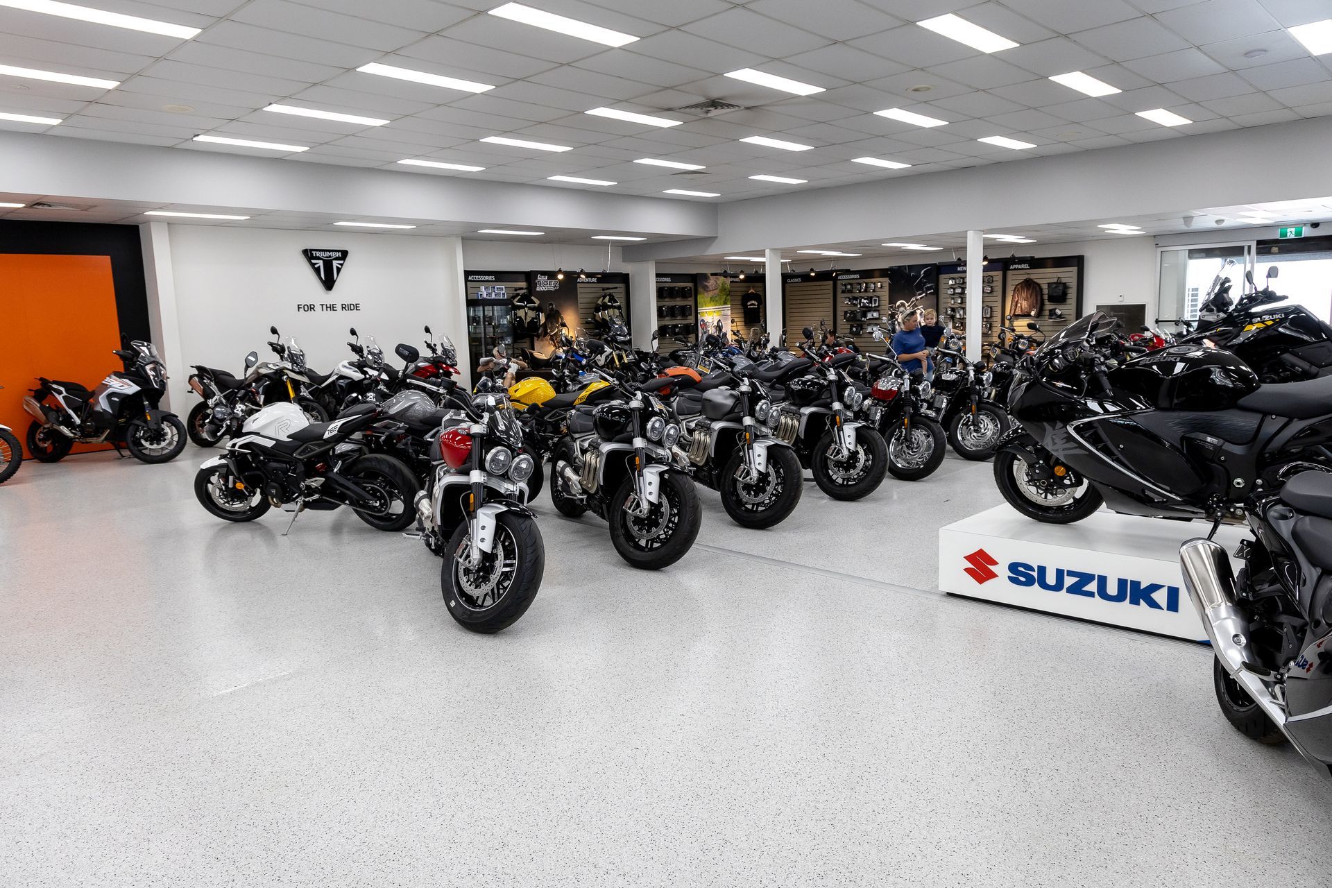 Motorcycle showroom with rows of bikes under bright lights, including a Suzuki display in front