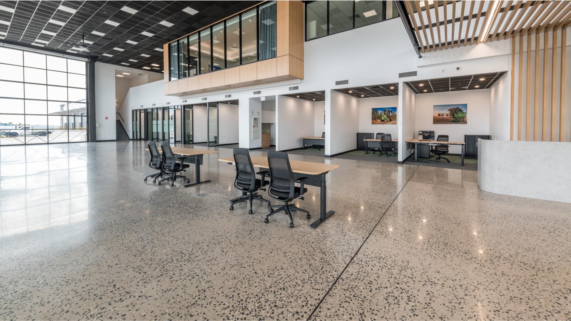 Modern lobby with glass walls, polished terrazzo floor, office chairs, and a staircase under a high ceiling Modern lobby with glass walls, polished terrazzo floor, office chairs, and a staircase under a high ceiling