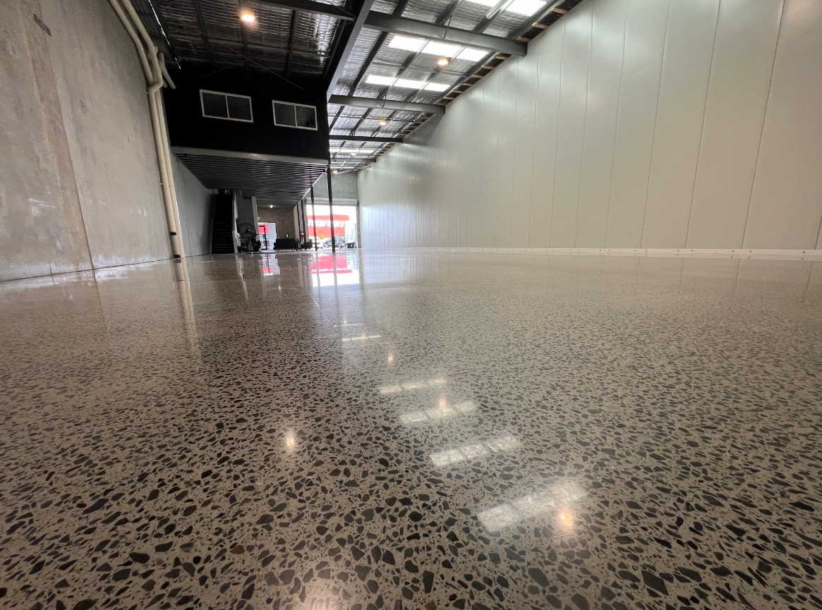 Polished speckled hallway with white walls and ceiling lights in an empty industrial interior