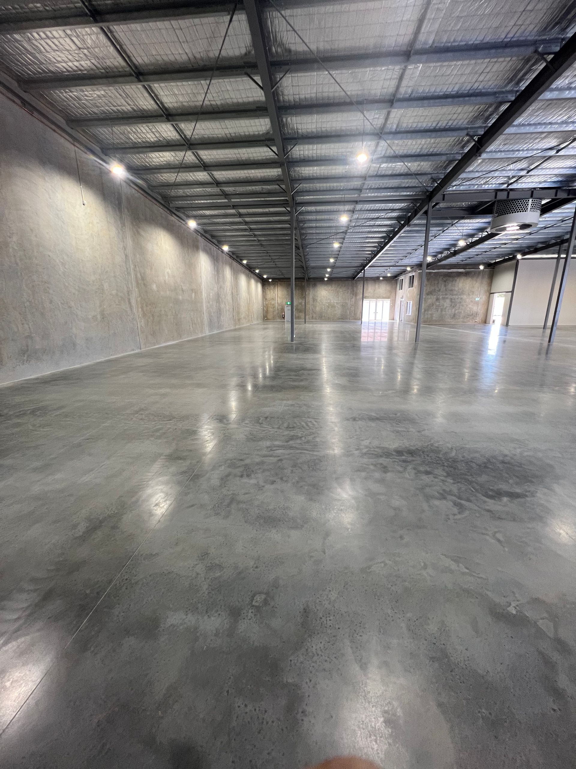 Empty industrial warehouse with polished concrete floor and metal roof beams
