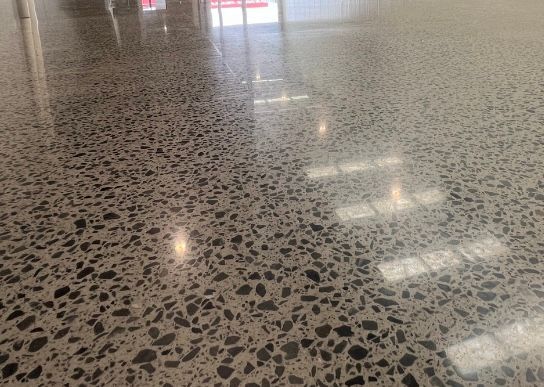 Polished speckled terrazzo floor reflecting overhead lights in a hallway