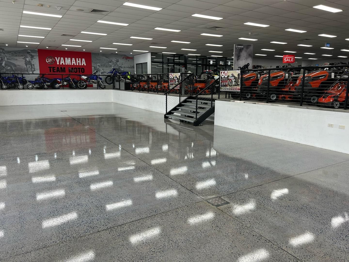 Motorcycle showroom with rows of bikes under bright ceiling lights and a glossy white floor