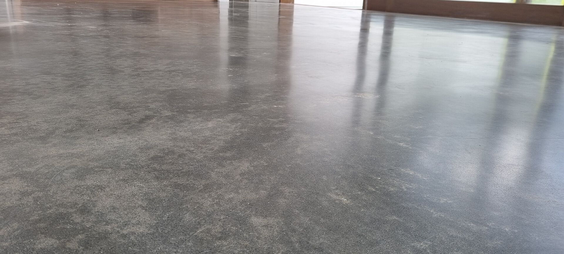 Wet gray concrete floor reflecting light in a large indoor space