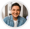 Smiling person in a denim shirt, framed in a circular profile photo indoors