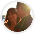 Two people smiling in warm sunlight, close together in a circular frame
