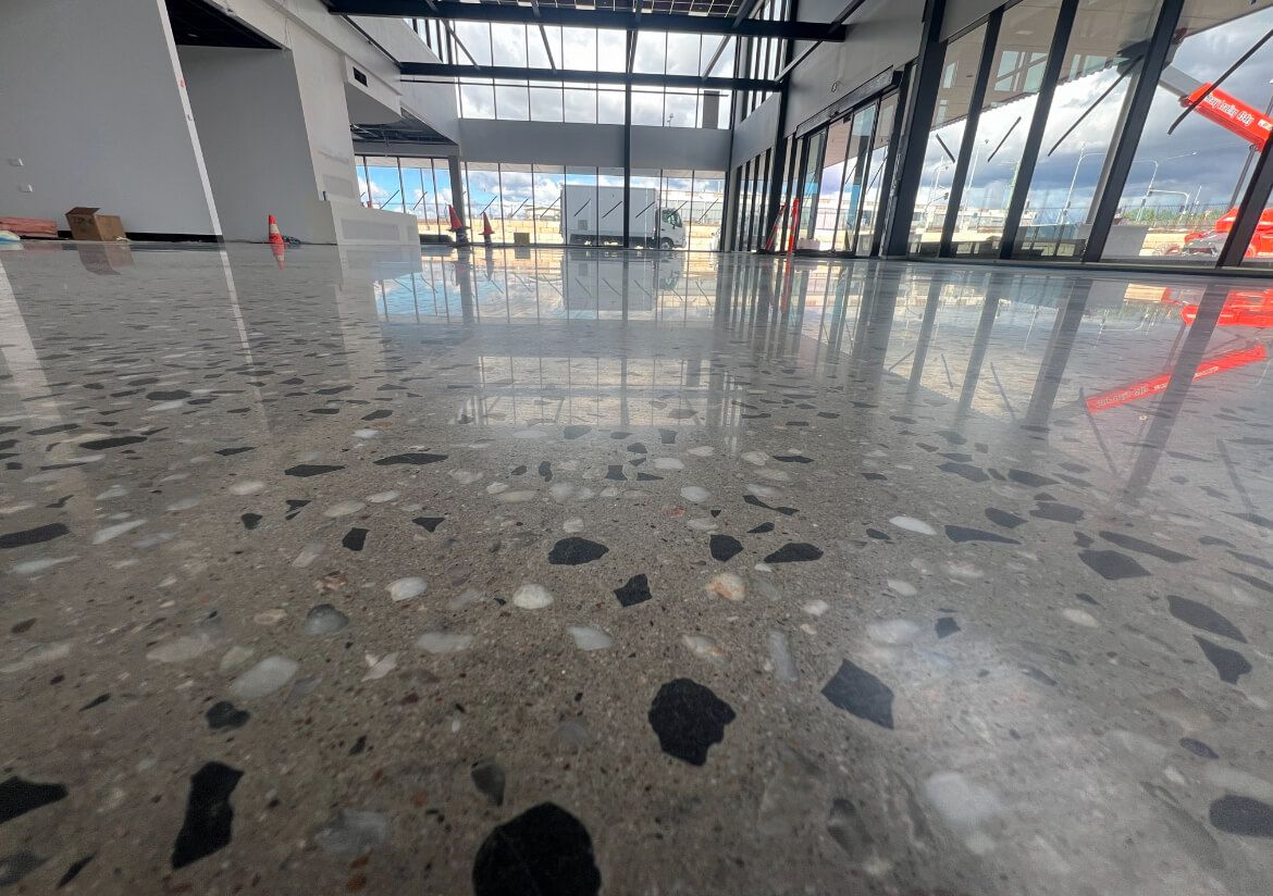 Empty modern lobby with glossy terrazzo floor and large glass windows.