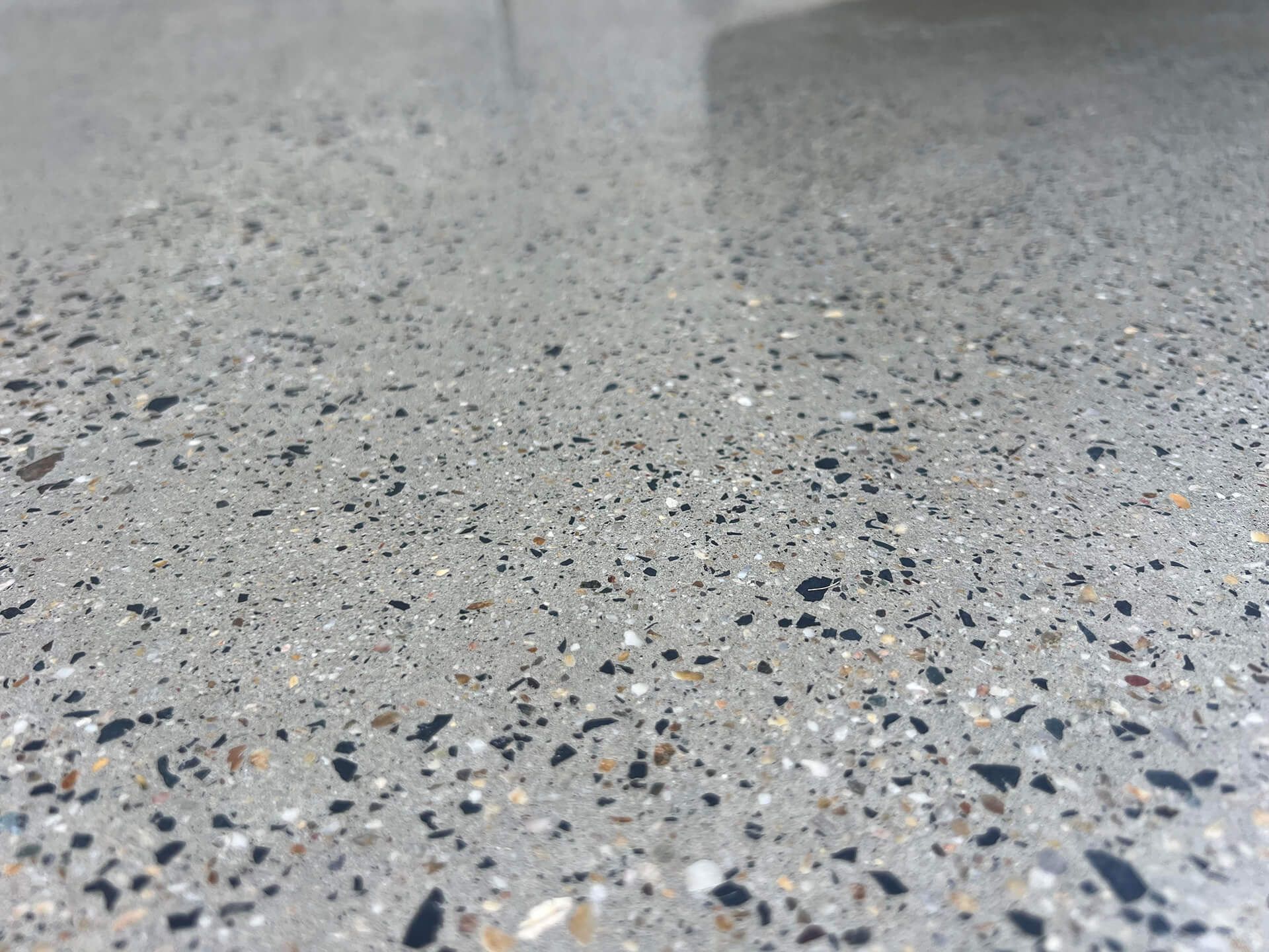 Close-up of speckled gray polished concrete floor with a smooth reflective surface
