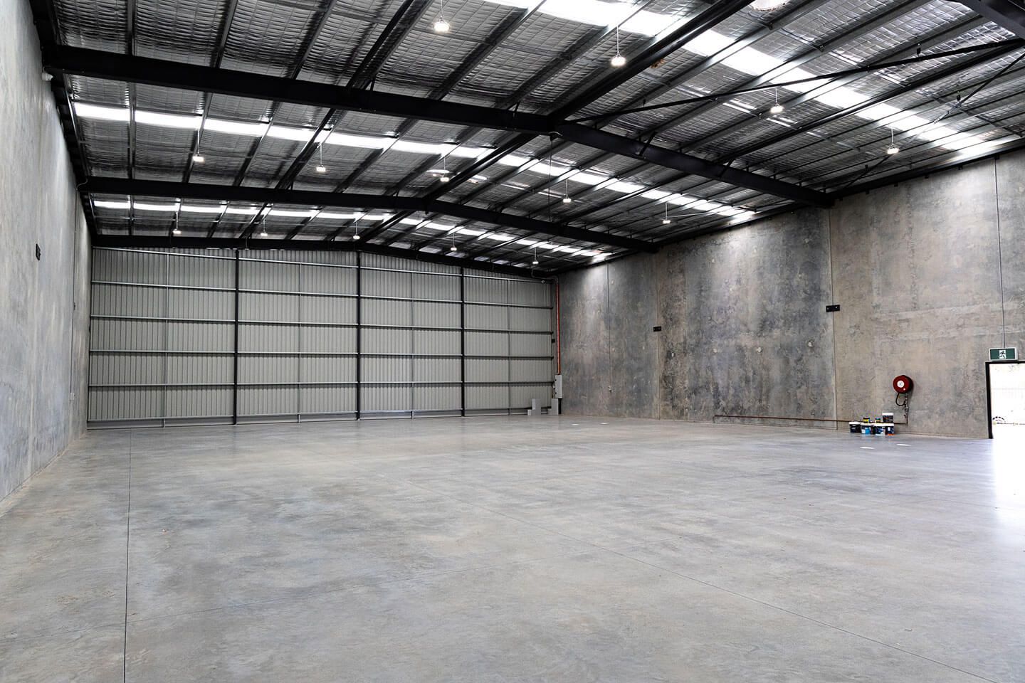 Empty industrial warehouse with concrete floor, metal walls, and a large roll-up door