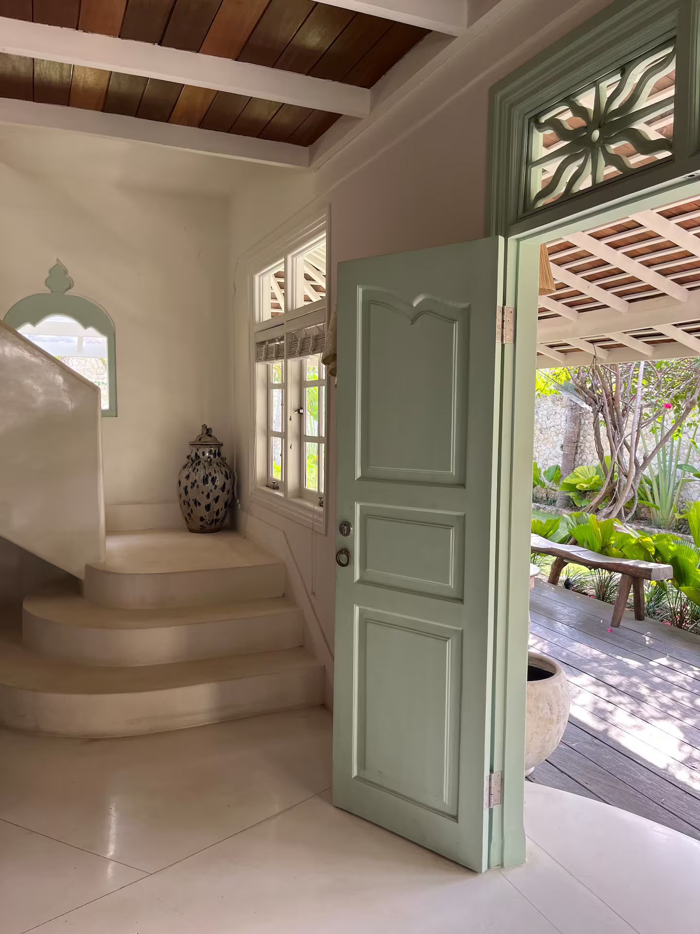 Interior doorway open to a garden view; light green door and trim, stairs, neutral walls, decorative lantern.