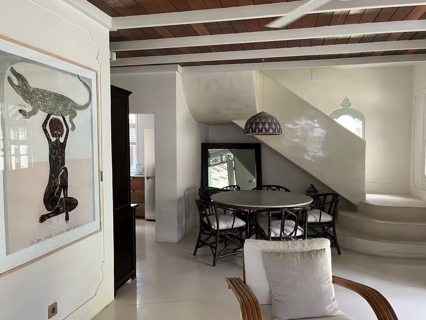 Bright interior with white walls, dark furniture, and a round dining table near stairs.