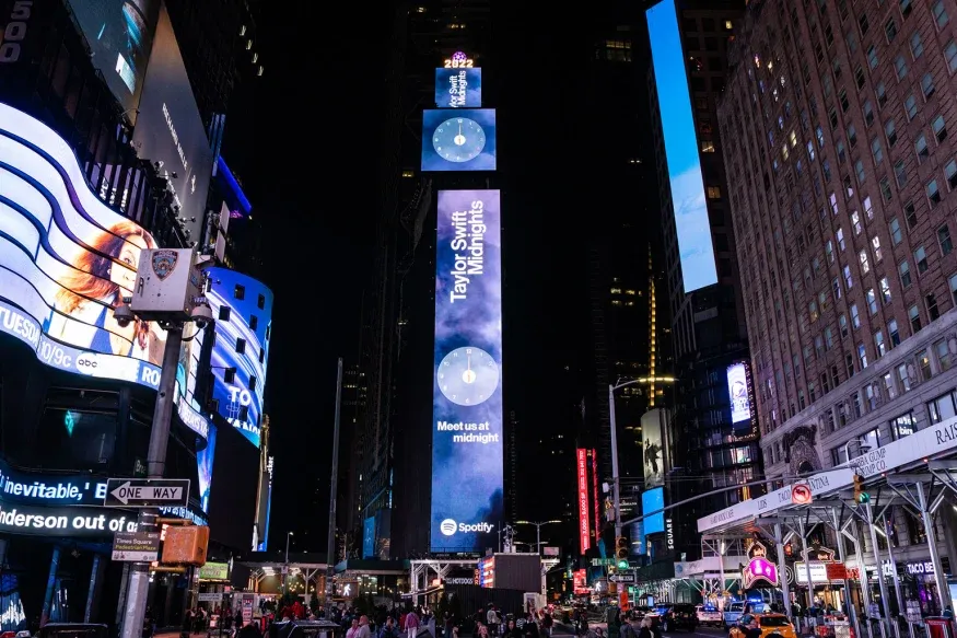 A busy city street at night with a large billboard in the middle of it.