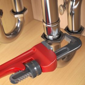 pllumber using an ajustable wrench to repair a wat