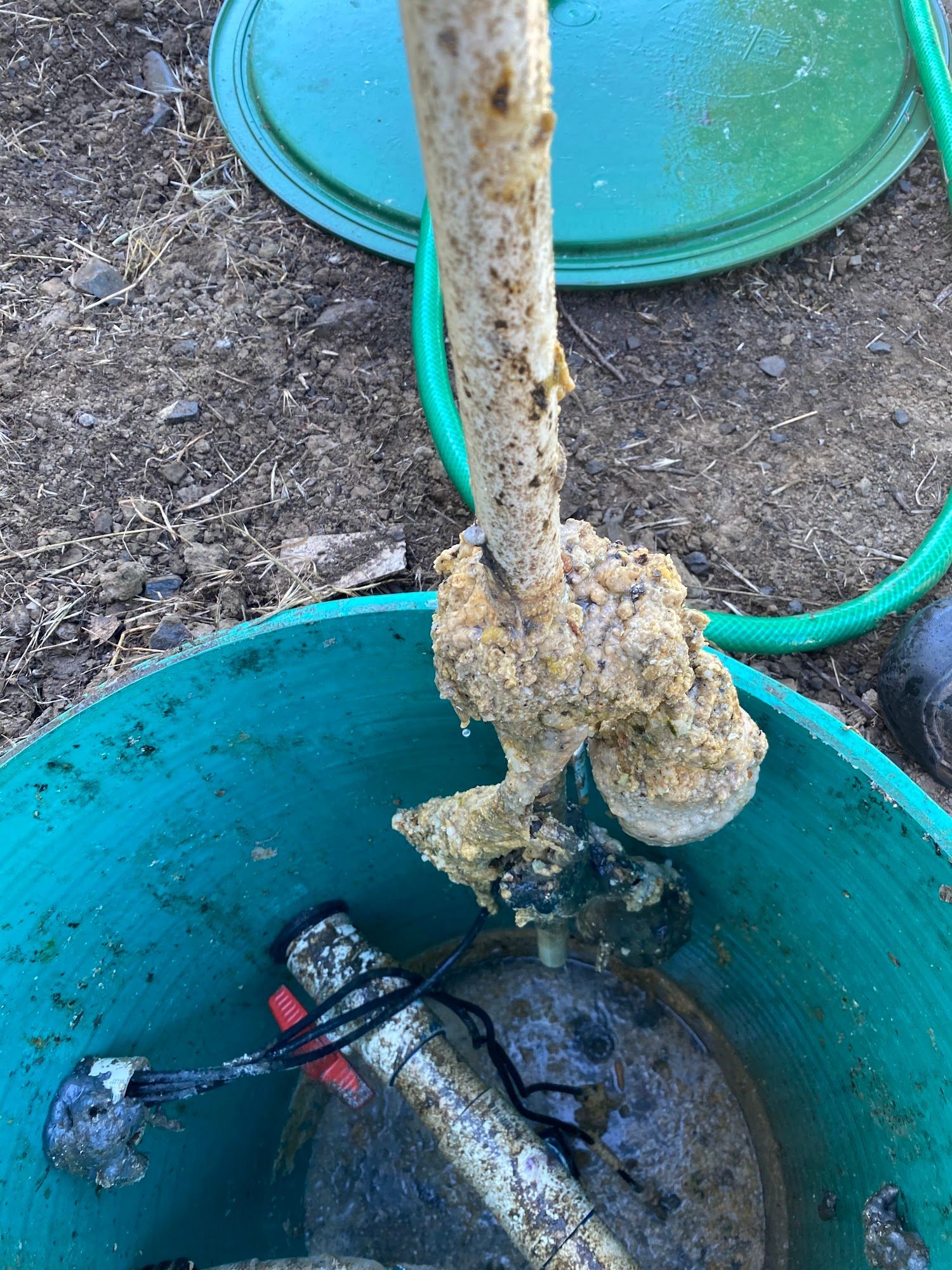Green septic tank with a white pipe covered in yellowish, crusty buildup.