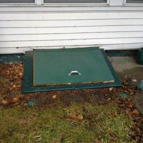 A green door with a handle is sitting in the grass next to a white house.