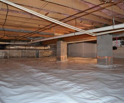 A basement with a plastic sheet on the floor and pipes coming out of the ceiling.