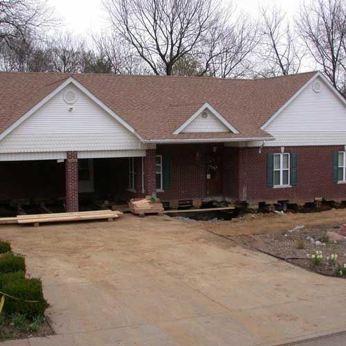 A brick house with a brown roof and white trim is under construction.
