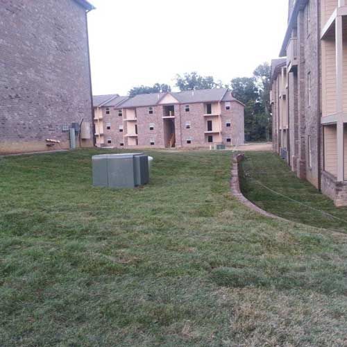 A large lawn in front of a row of buildings.