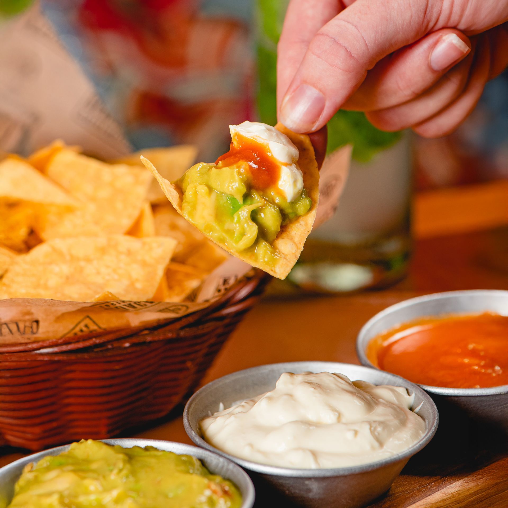 Mergulhar um nacho no guacamole com salsa e creme azedo à parte.