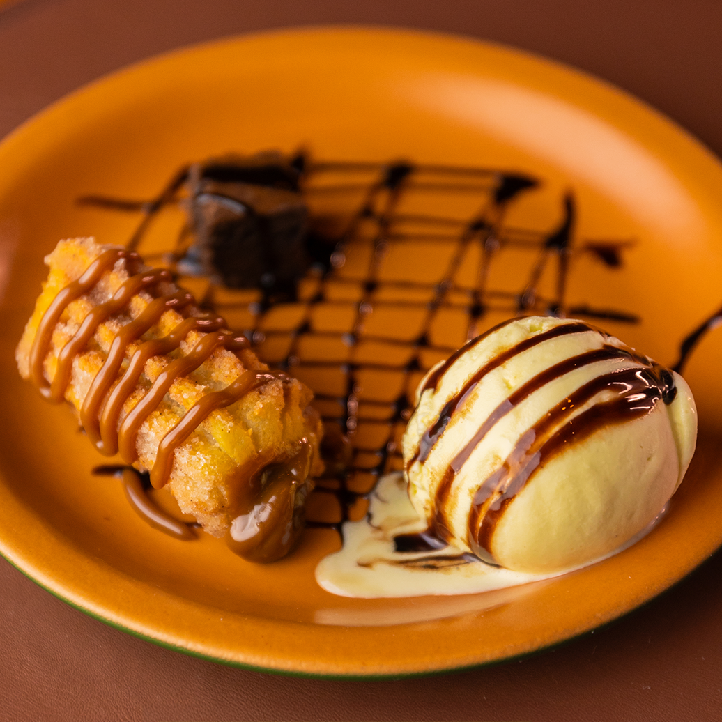 Duas sobremesas com calda de caramelo e chocolate servidas em um prato laranja.