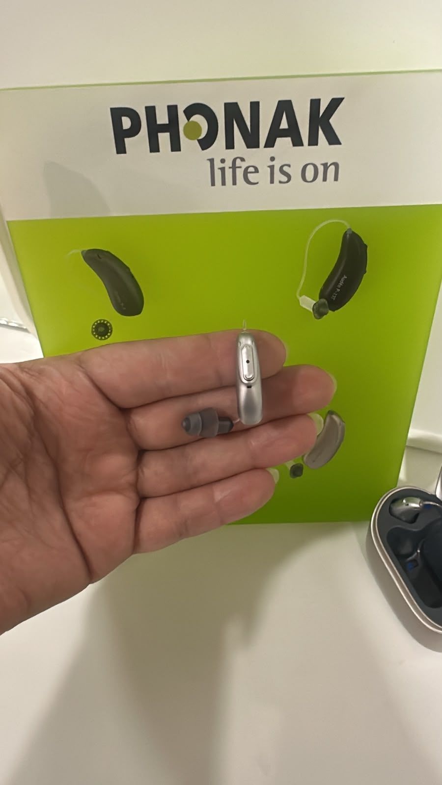 Audífono Phonak Audéo sobre la palma de la mano, mostrando su tamaño discreto, en el consultorio en Tijuana