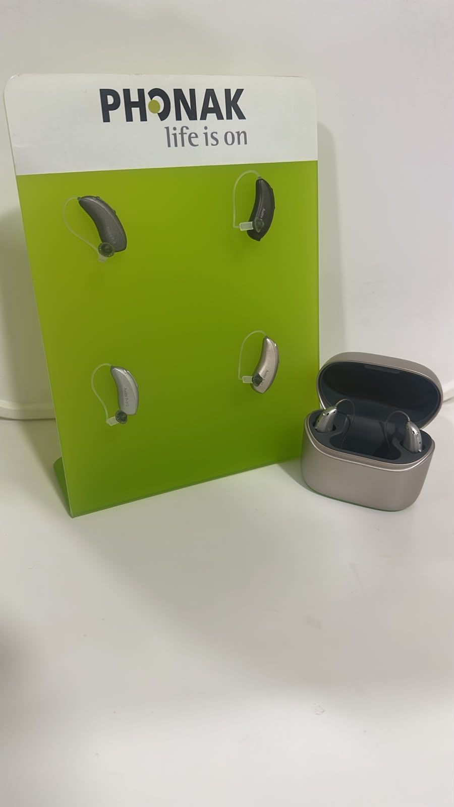 Audífonos Phonak recargables dentro de su estuche de carga junto al exhibidor, en el consultorio en Tijuana
