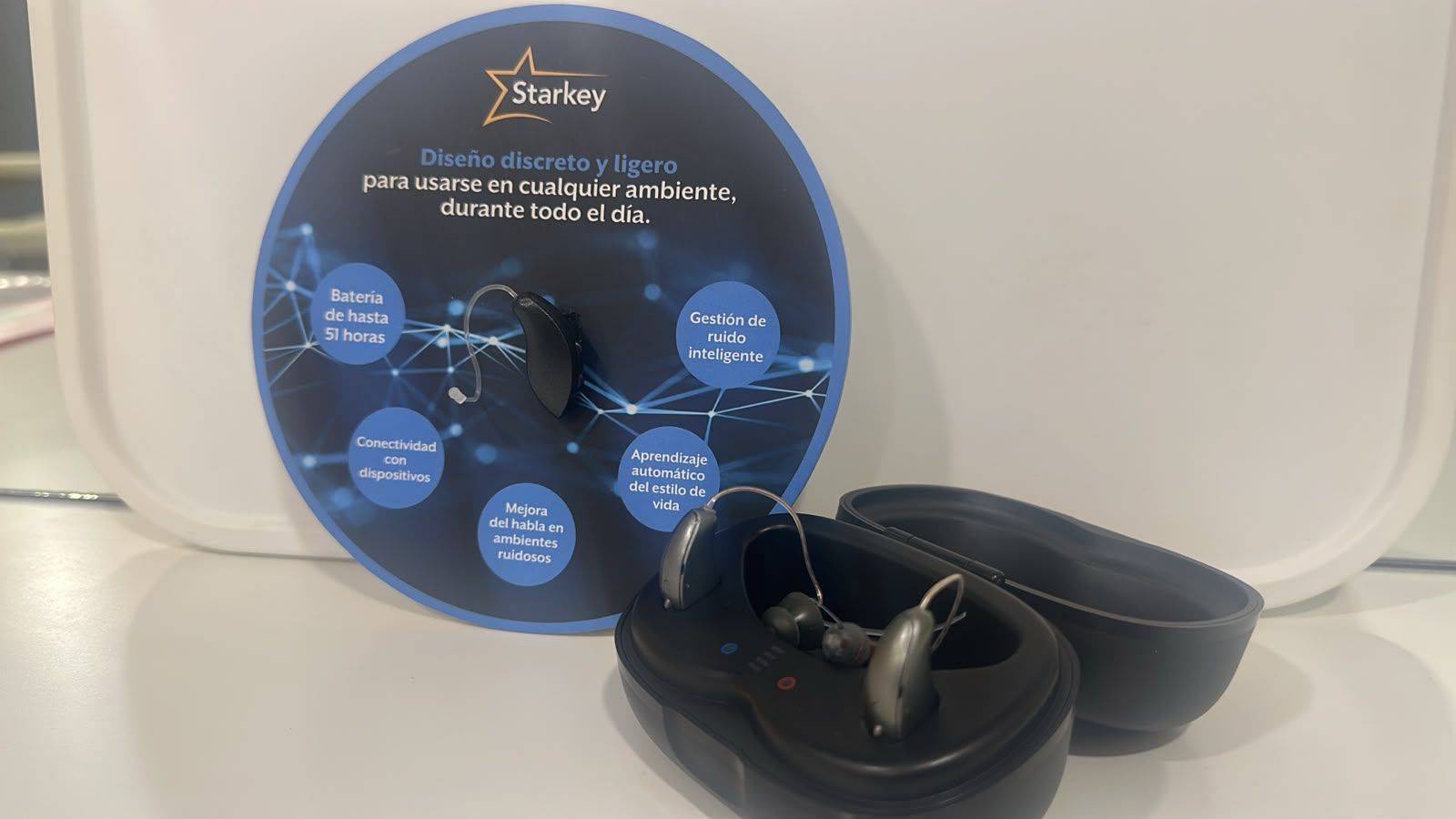 Exhibidor de audífonos Starkey con estuche de carga en el consultorio de la Dra. Gabriela Castillo en Tijuana