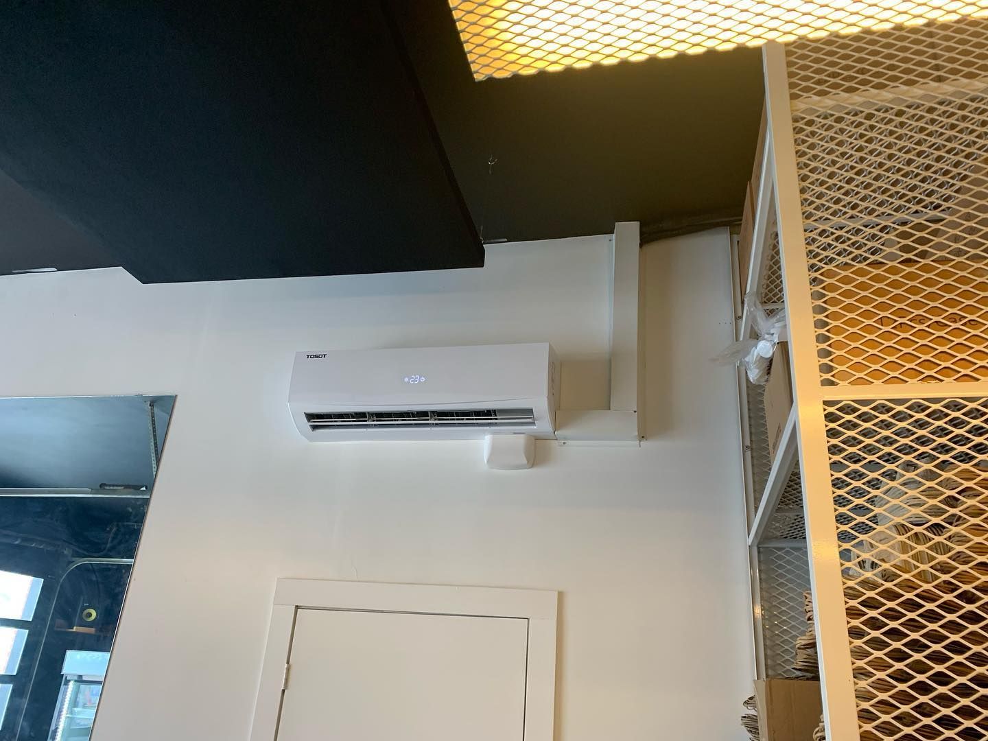 A white air conditioner is mounted on a white wall in a room.