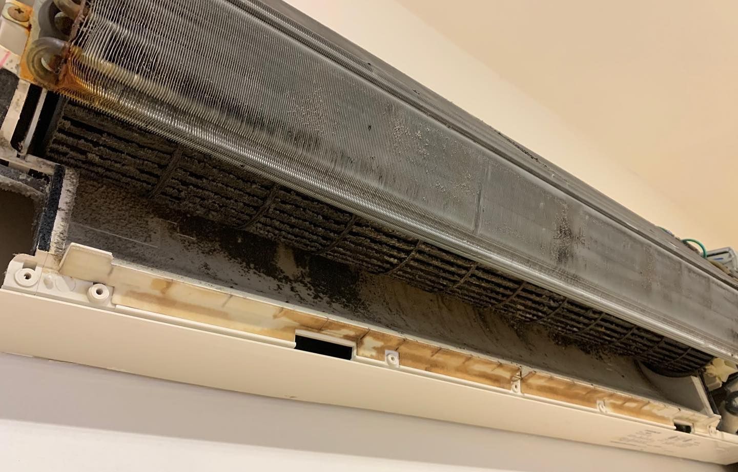 A close up of a dirty air conditioner on a wall.