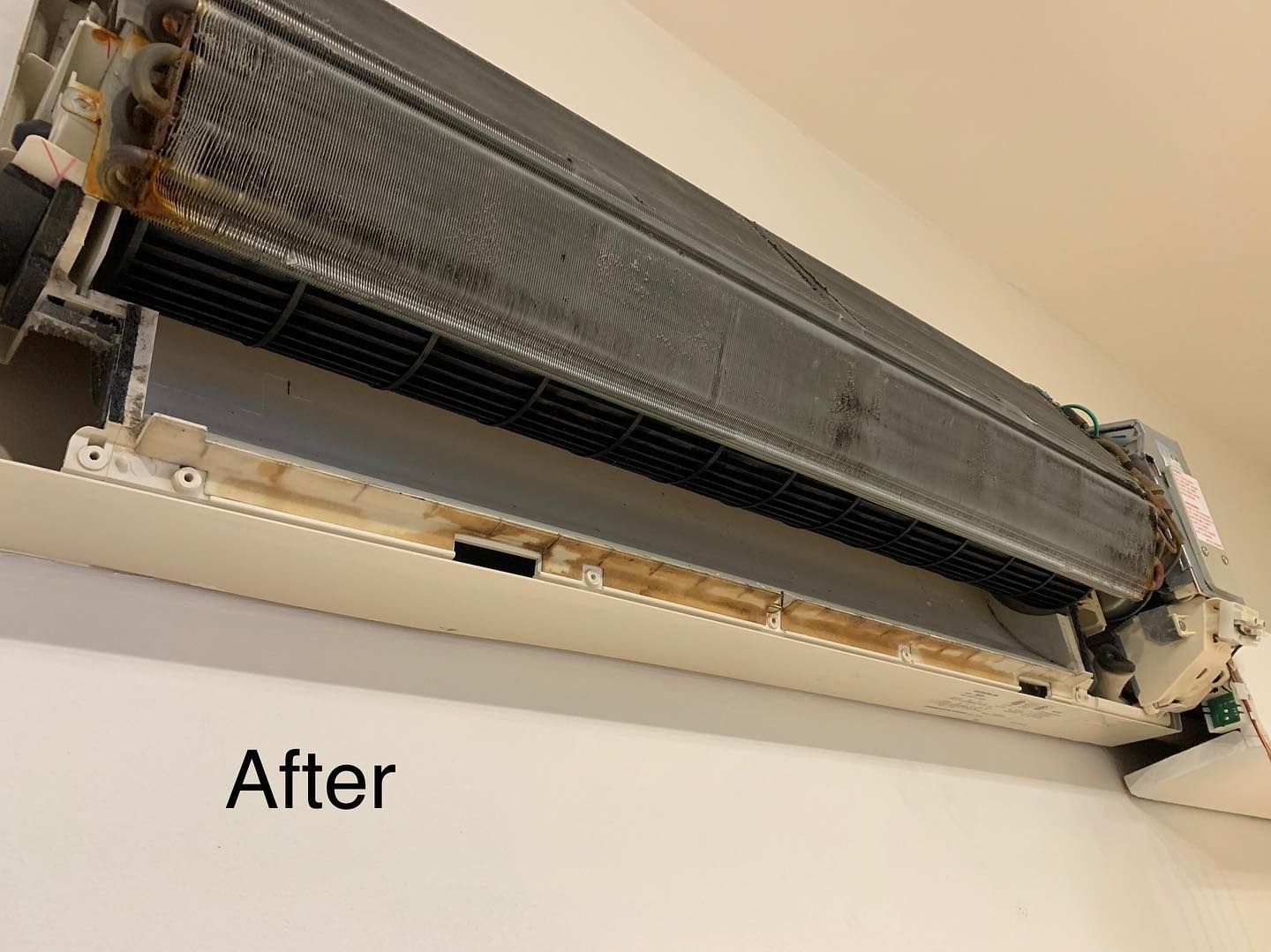 A picture of a dirty air conditioner hanging on a wall.