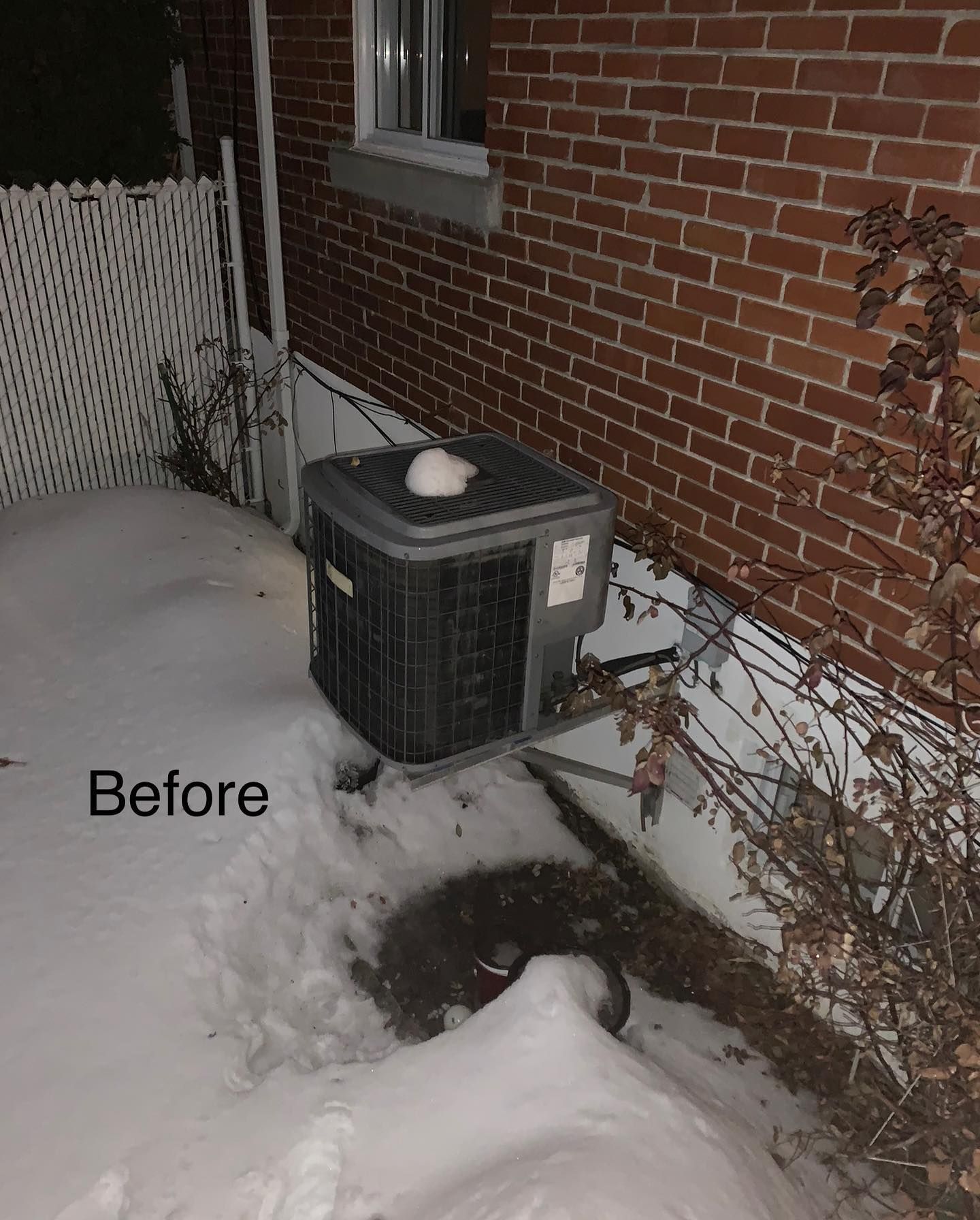 A picture of a house with a air conditioner in the snow.