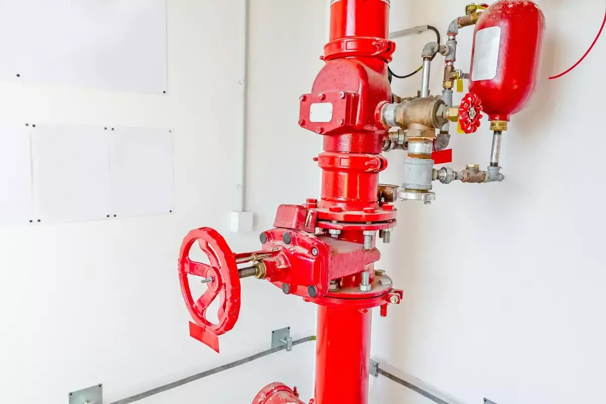 A red fire hydrant is sitting in a room next to a white wall.