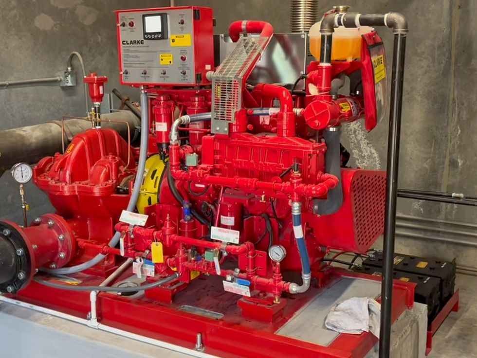 A red engine is sitting in a room with many pipes A red engine is sitting in a room with many pipes