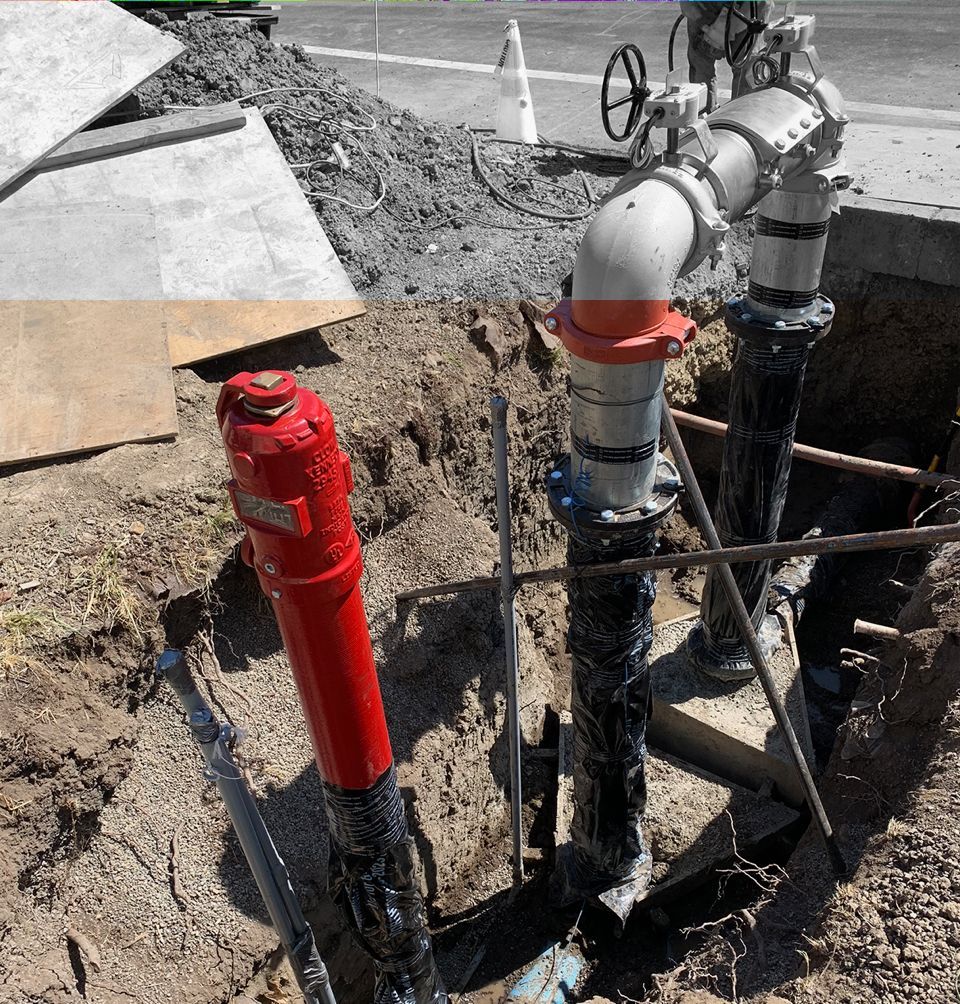 A red fire hydrant is sitting in the dirt next to a bunch of pipes