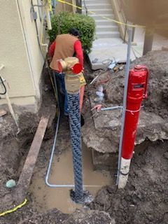 A man is standing in the dirt next to a red fire hydrant.
