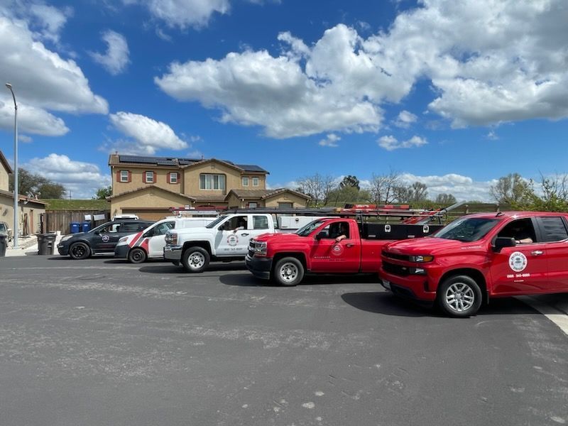 A row of red and white trucks are parked in a parking lot.