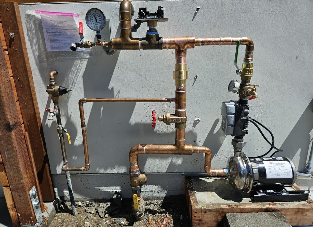 A wall with copper pipes and a pump on it
