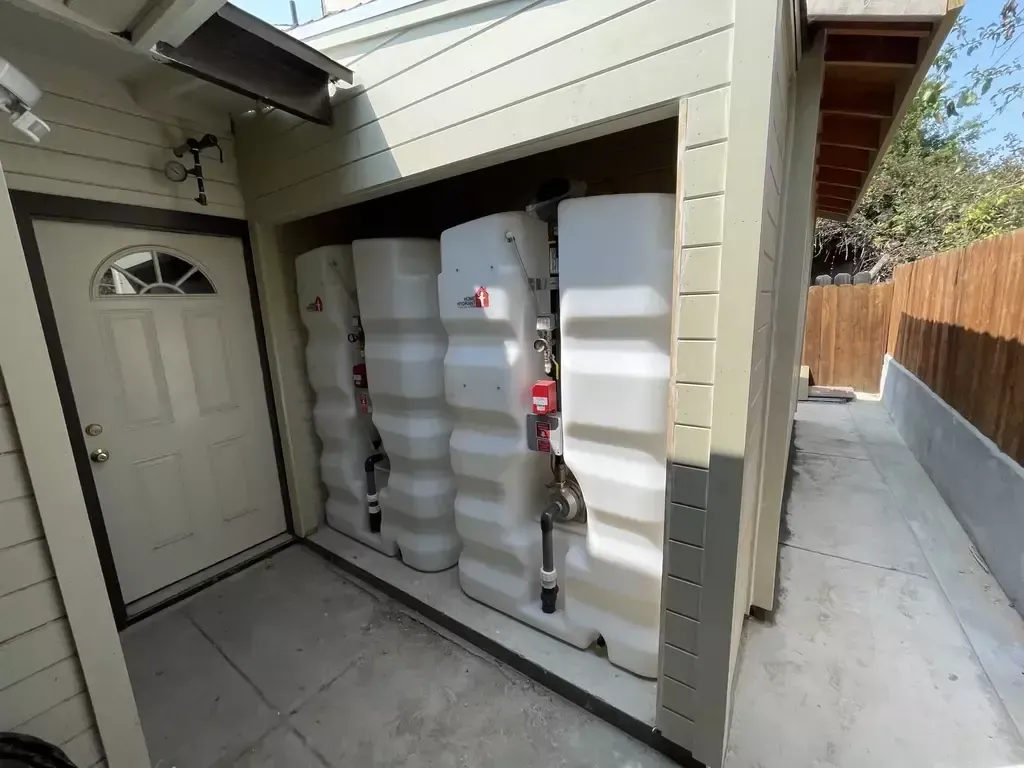A row of white tanks are stacked on top of each other in a garage.