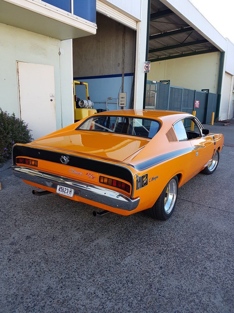 Orange classic muscle car parked outside a building with open garage doors