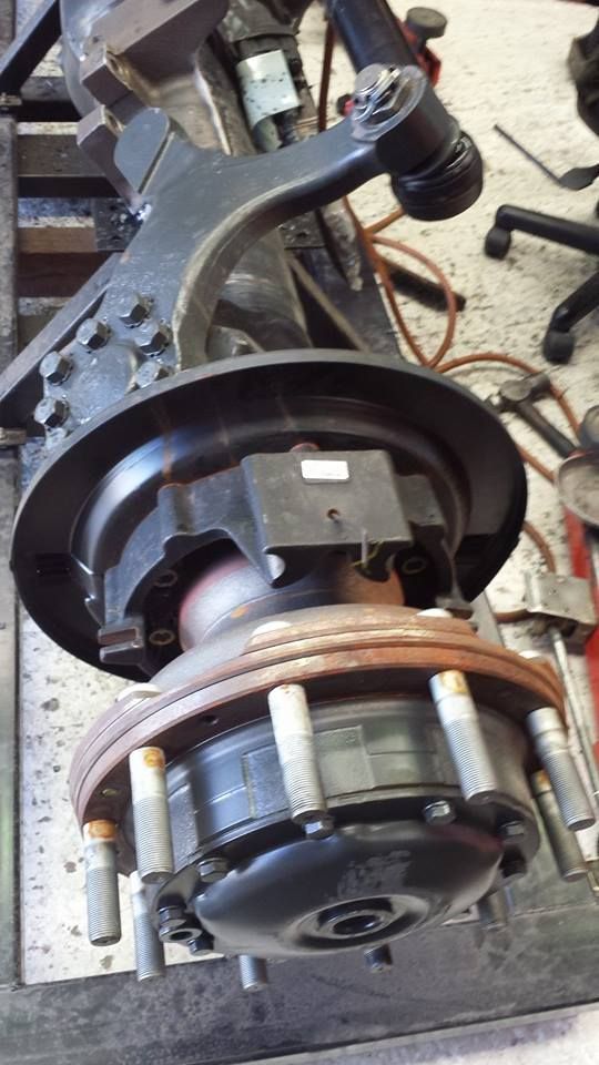 Close-up of a mechanical rotor assembly with copper coils, black housing, and metal arms on a workbench