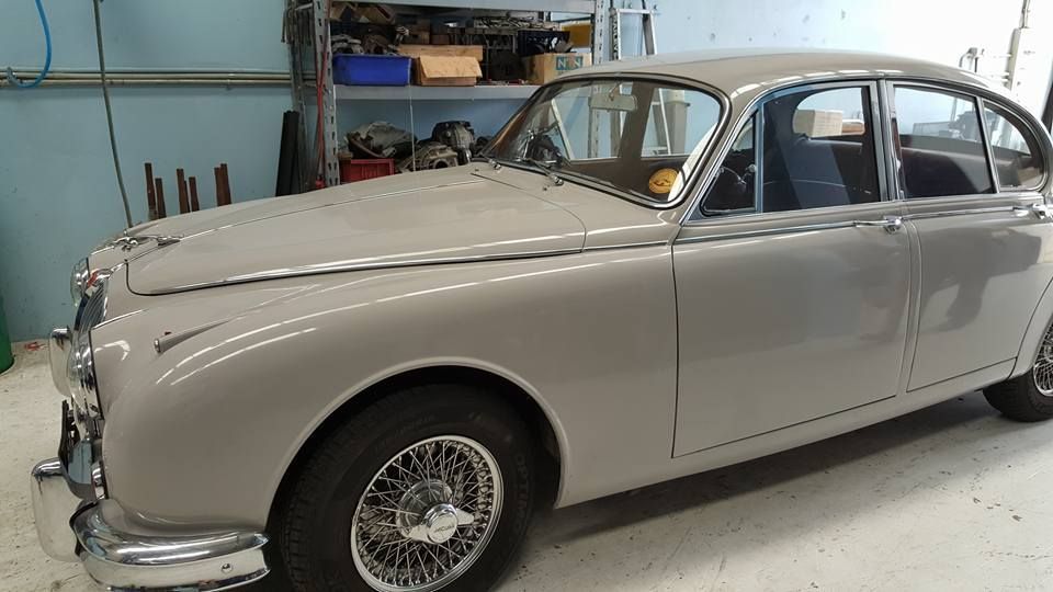 Classic beige vintage sedan in a garage, side view with wire-spoke wheels.