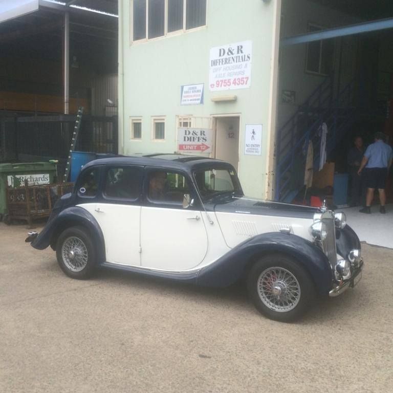 Classic black-and-white vintage car parked outside a garage building