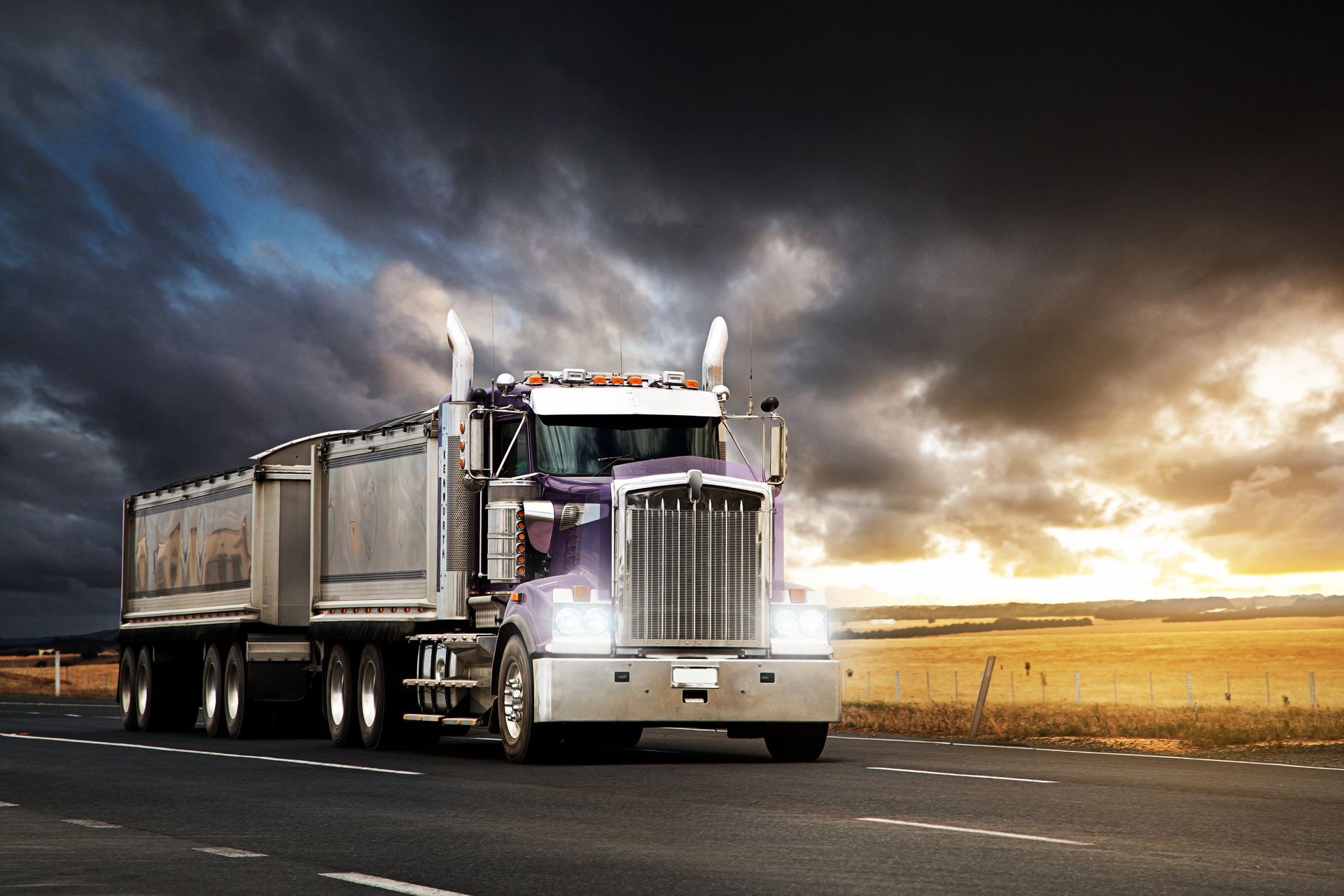 Silver vintage car in a garage, viewed from the rear side beside shelves and tools.