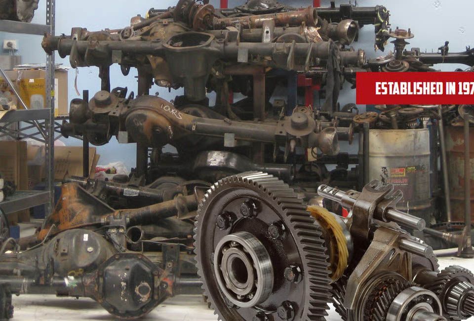 Rusty engine parts and gears displayed in a workshop, with a red sign in the background.