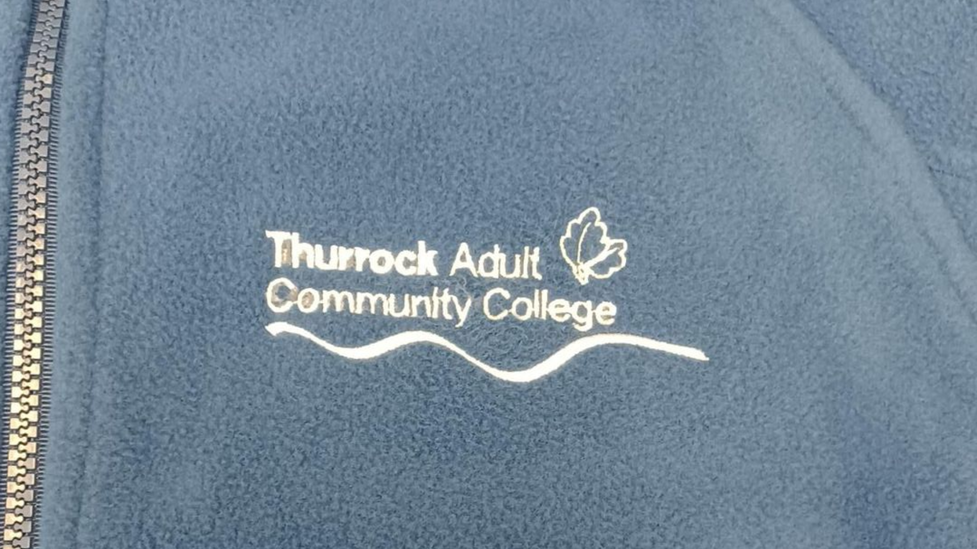 Blue fleece jacket with Thurrock Adult Community College logo embroidered in white